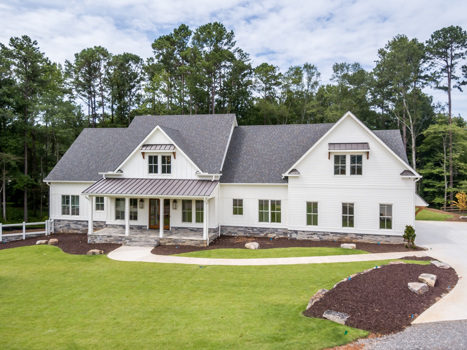White farmhouse with a welcoming porch surrounded by pine trees