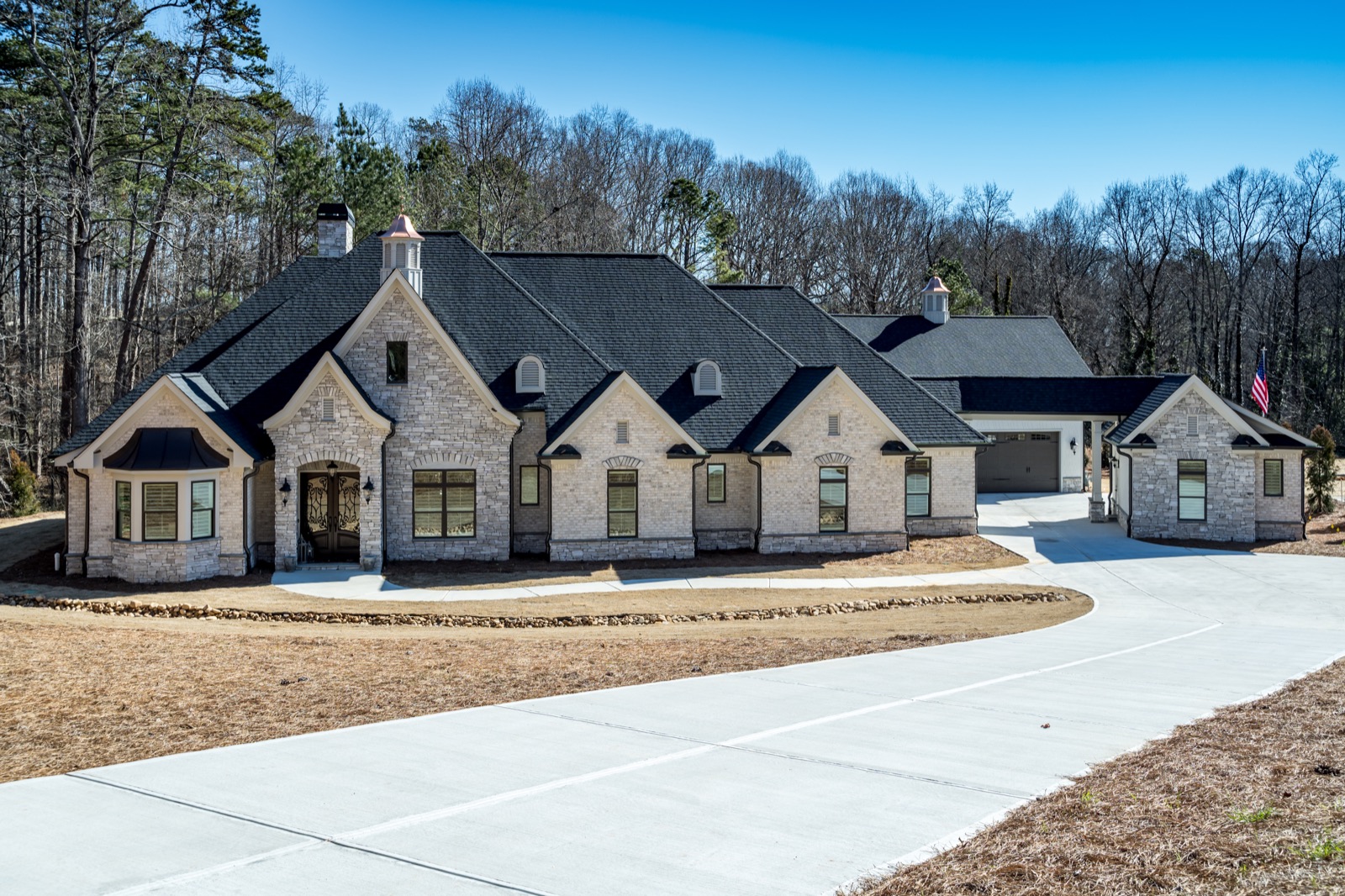 Expansive brick custom home with arched entrance and multiple gables