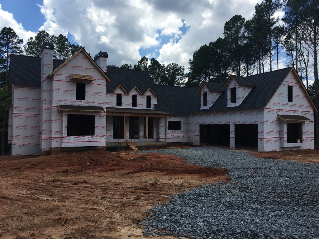 Custom home with roof installed and exterior building wrap in place