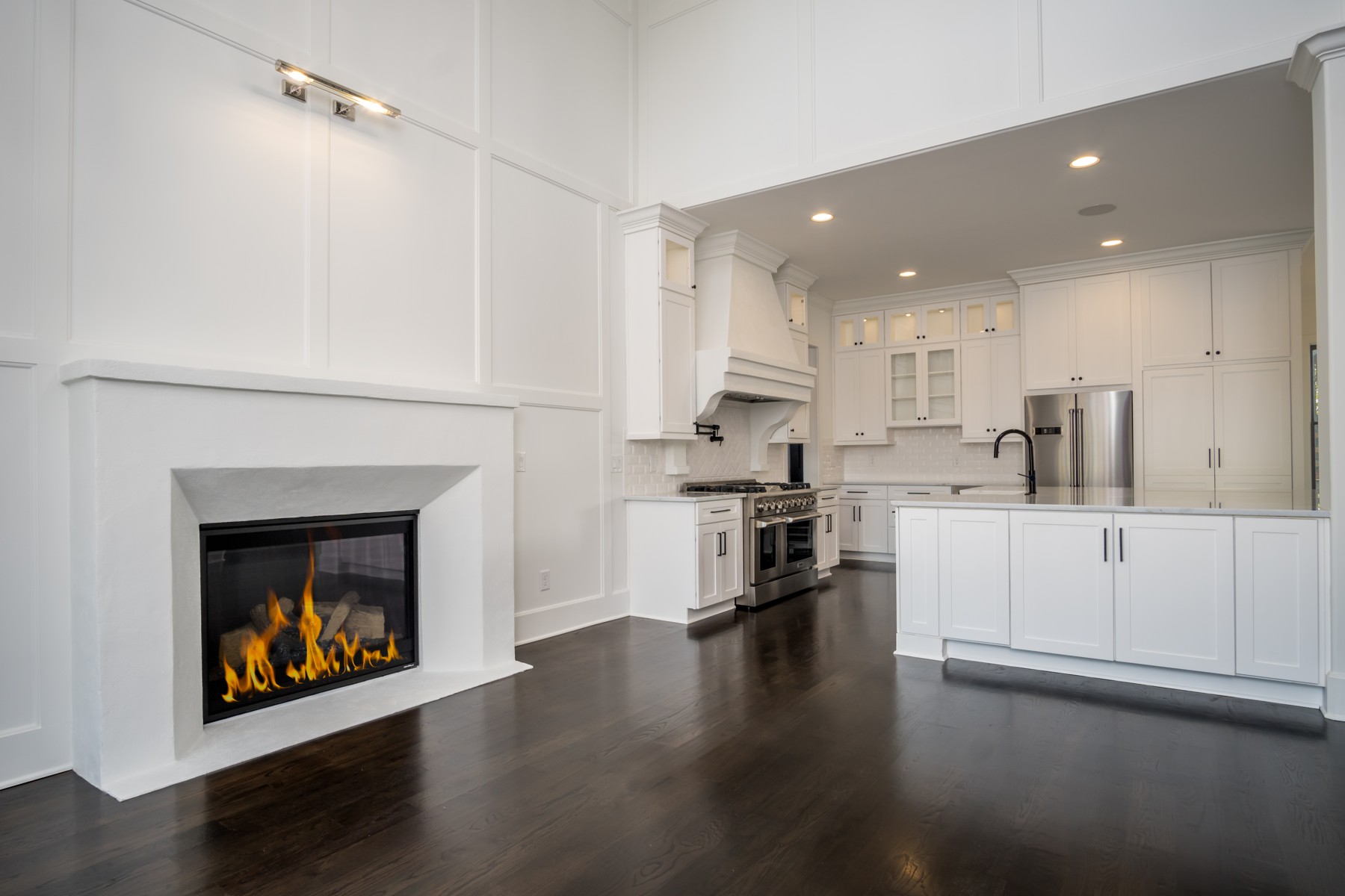 White custom kitchen beside a paneled fireplace