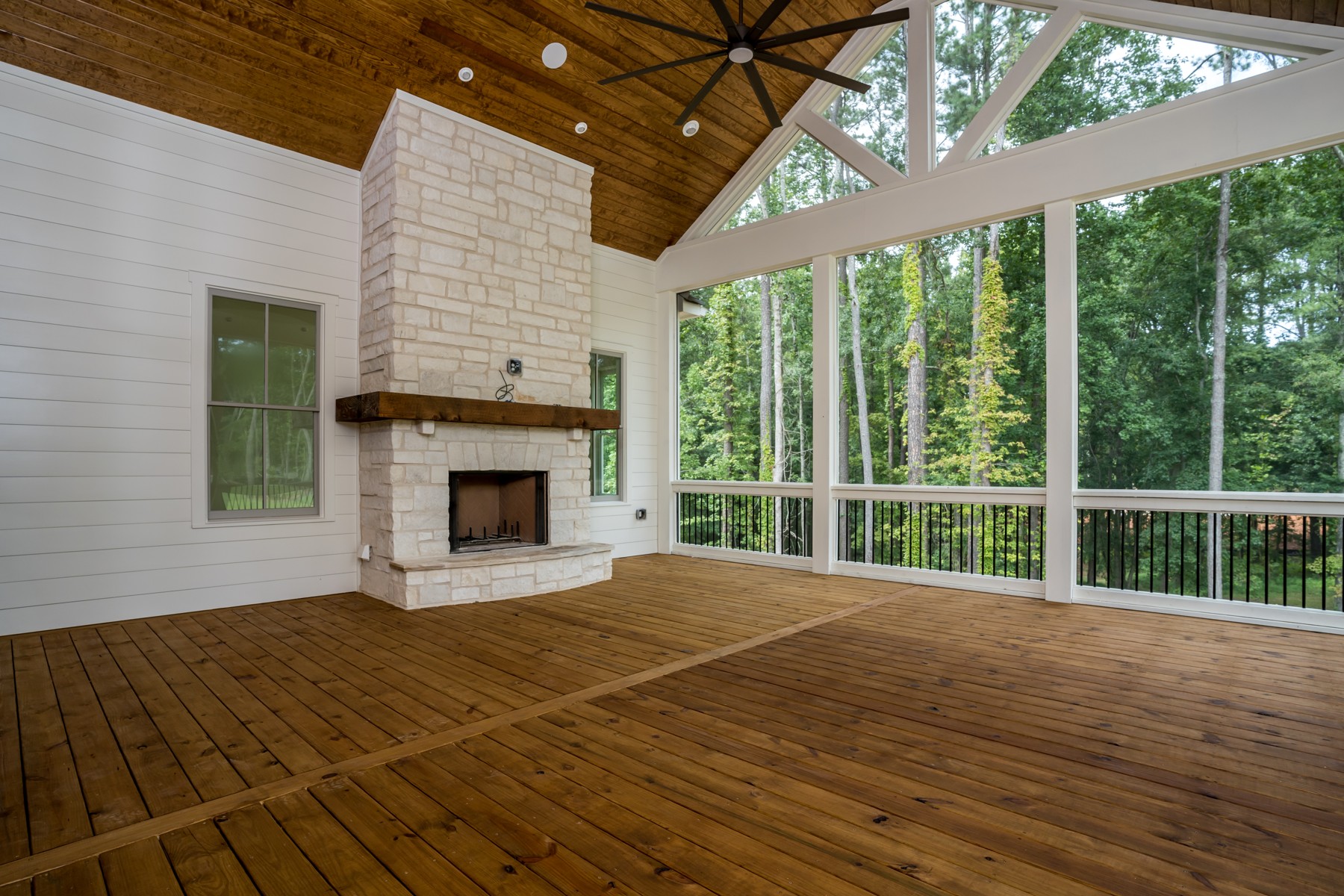 Screened outdoor living room with wood ceiling and stone fireplace